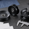 Generic aftermarket mower pulleys, blank specification cards, and a caliper arranged on an industrial workbench
