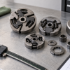 Generic aftermarket chainsaw clutch assemblies beside a caliper and blank fitment checklist on a clean workbench